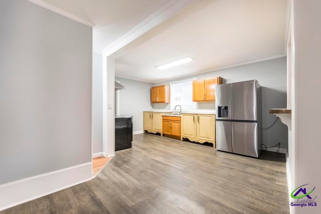 kitchen featuring stainless steel refrigerator with ice dispenser, light hardwood / wood-style floors, ornamental molding, and sink