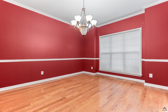 empty room featuring hardwood / wood-style flooring, ornamental molding, and an inviting chandelier