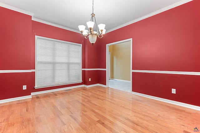 spare room featuring a notable chandelier, wood-type flooring, and crown molding