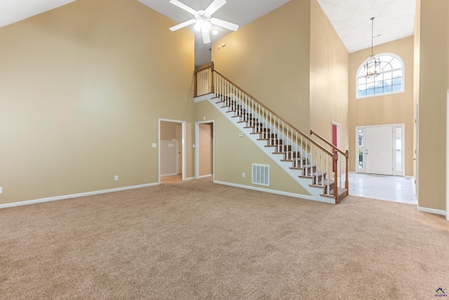 unfurnished living room featuring carpet, ceiling fan with notable chandelier, and high vaulted ceiling