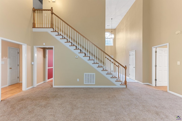 interior space with carpet flooring, a towering ceiling, and a notable chandelier