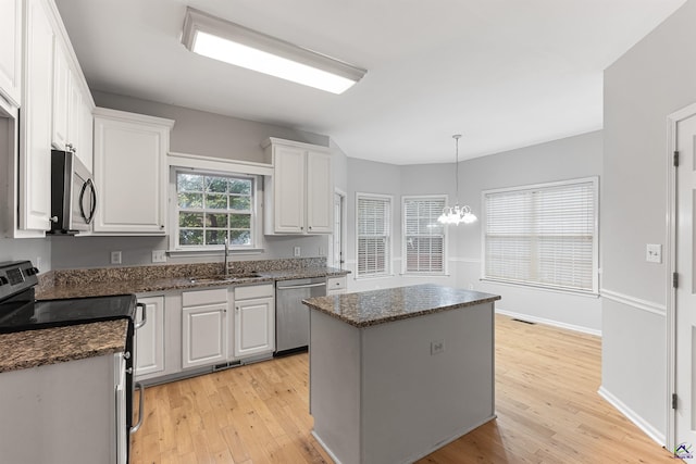 kitchen featuring light wood-type flooring, stainless steel appliances, a kitchen island, sink, and white cabinetry