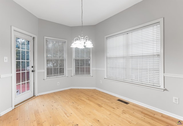 unfurnished dining area with hardwood / wood-style floors and a notable chandelier