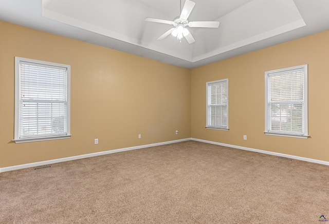 unfurnished room featuring ceiling fan, a raised ceiling, and carpet floors