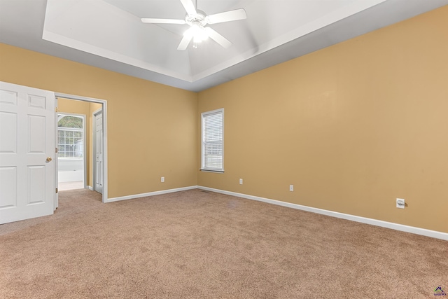 empty room with carpet, ceiling fan, and a raised ceiling