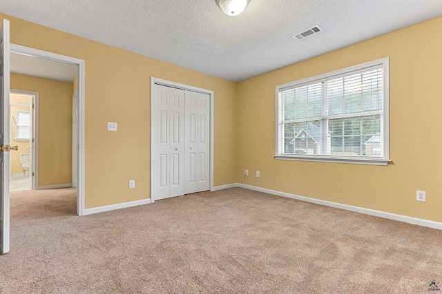 unfurnished bedroom with a textured ceiling, light colored carpet, and a closet