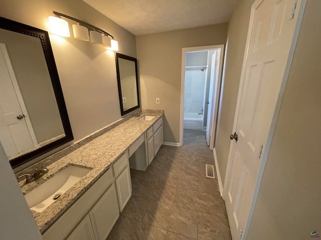 bathroom featuring a textured ceiling, vanity, and shower / washtub combination