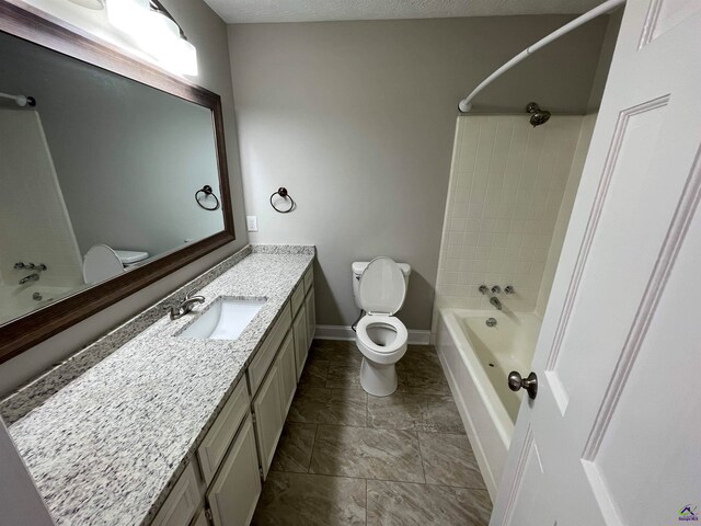 full bathroom featuring a textured ceiling, vanity, toilet, and tiled shower / bath