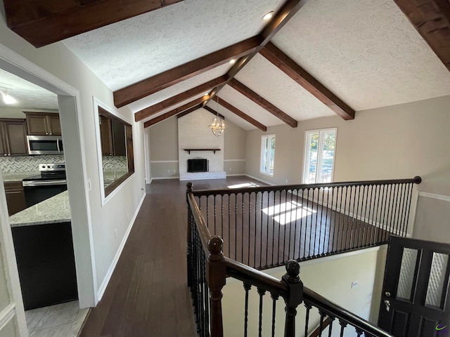 corridor featuring a chandelier, dark hardwood / wood-style flooring, lofted ceiling with beams, and a textured ceiling