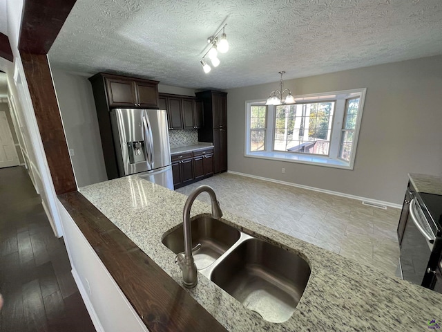 kitchen featuring dark wood-type flooring, sink, light stone countertops, a textured ceiling, and stainless steel appliances