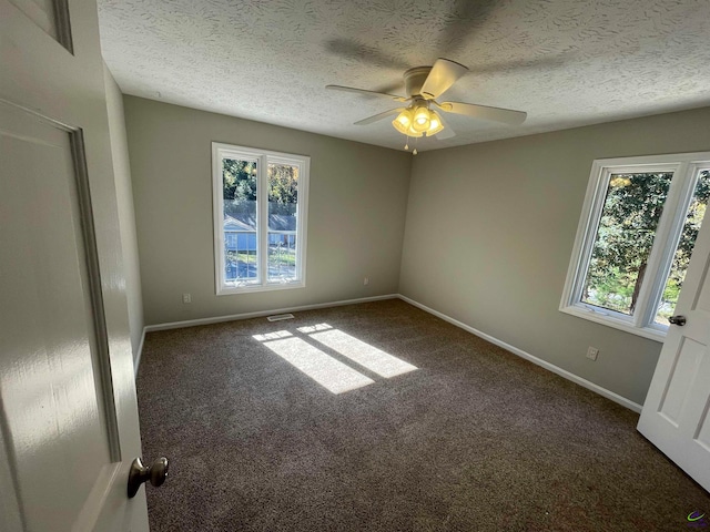 empty room with ceiling fan and dark colored carpet