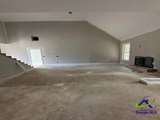 unfurnished living room with a fireplace, vaulted ceiling, and stairs