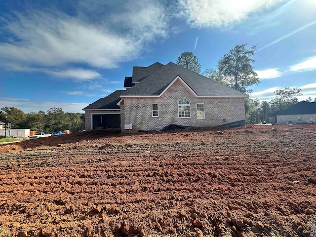 view of home's exterior featuring brick siding and roof with shingles