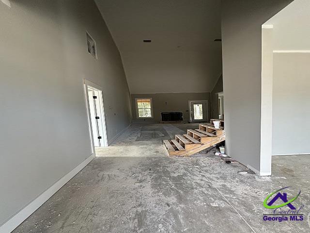 unfurnished living room featuring a towering ceiling and baseboards