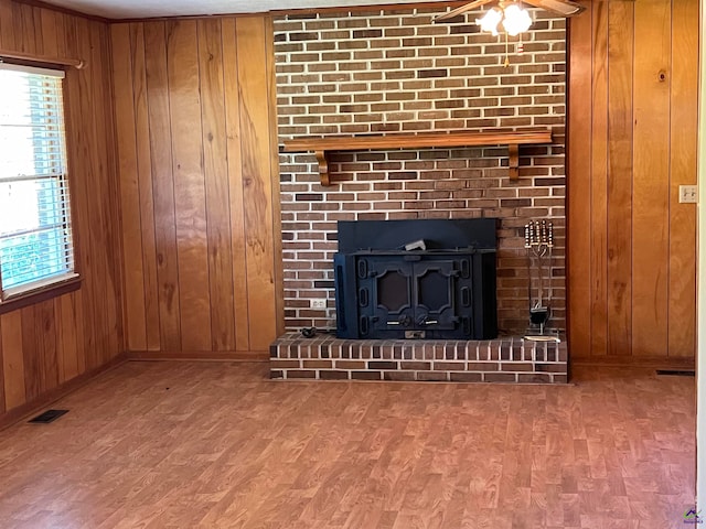 details featuring ceiling fan, wood walls, wood-type flooring, and a brick fireplace