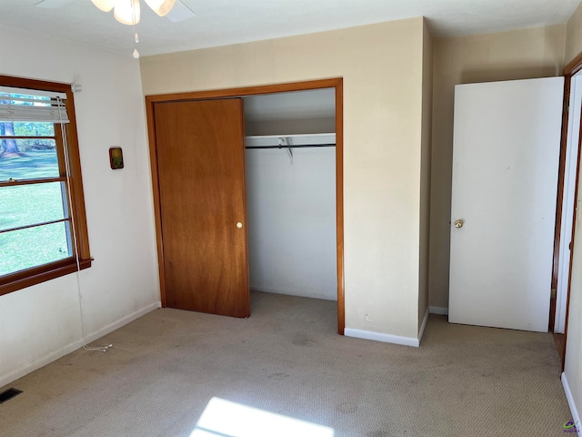 unfurnished bedroom with ceiling fan, a closet, and light colored carpet