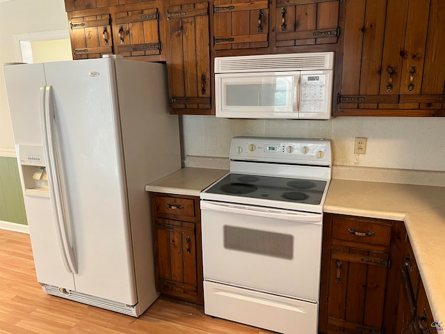 kitchen featuring light wood-type flooring, white appliances, and backsplash