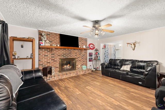 living room with a fireplace, hardwood / wood-style floors, a textured ceiling, and ceiling fan