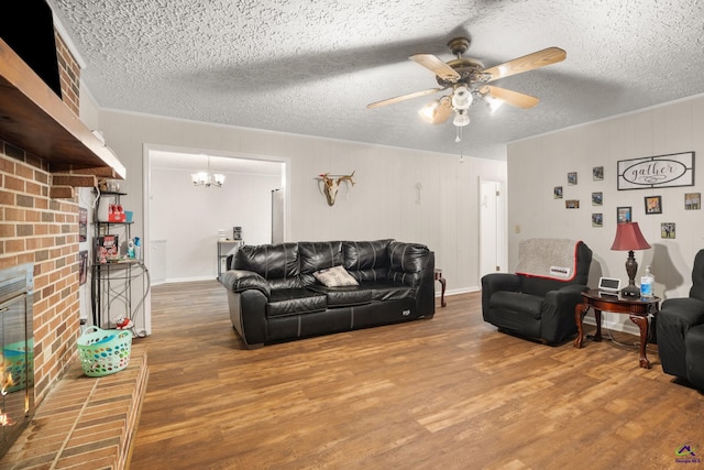 living room with hardwood / wood-style floors, ceiling fan with notable chandelier, a fireplace, and a textured ceiling