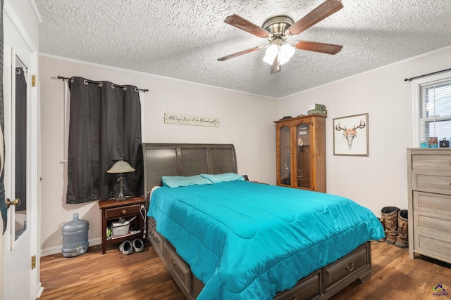 bedroom featuring a textured ceiling, crown molding, ceiling fan, and dark wood-type flooring