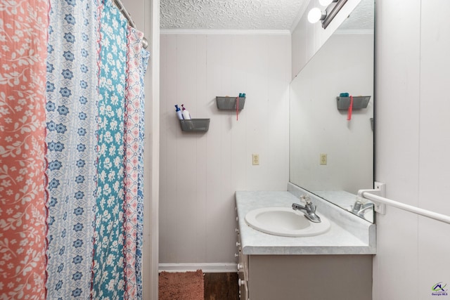 bathroom featuring crown molding, a textured ceiling, wooden walls, vanity, and hardwood / wood-style flooring