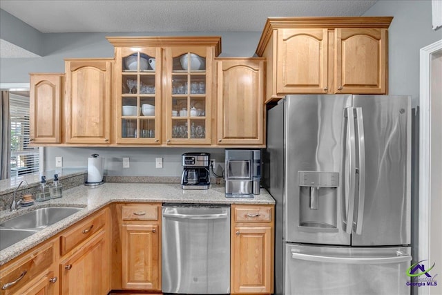 kitchen with light brown cabinetry, light stone counters, sink, and stainless steel appliances