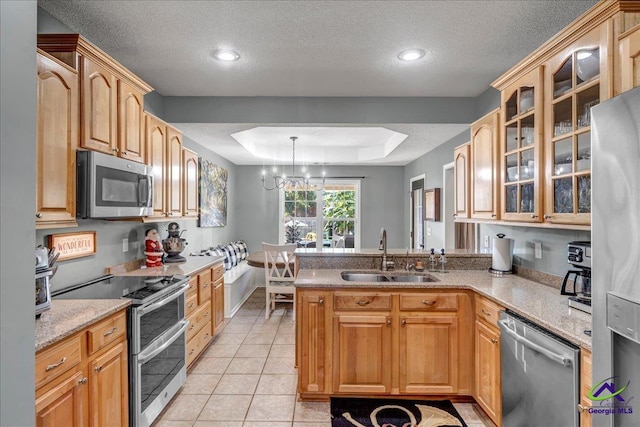 kitchen with a textured ceiling, stainless steel appliances, sink, pendant lighting, and a chandelier