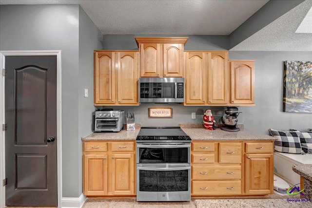 kitchen featuring light brown cabinets, a textured ceiling, and appliances with stainless steel finishes