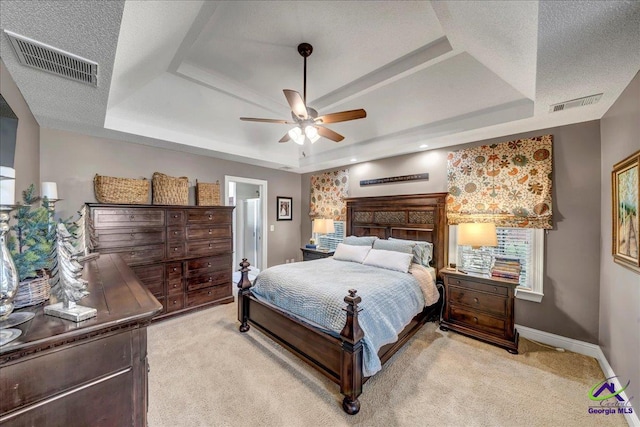 bedroom with a raised ceiling, light carpet, and ceiling fan