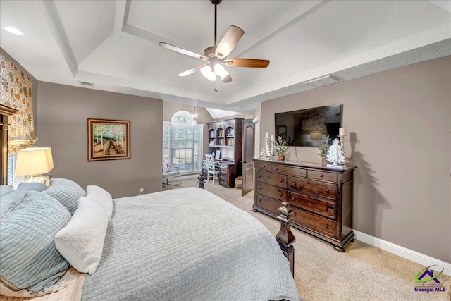 bedroom with a raised ceiling, ceiling fan, and light colored carpet