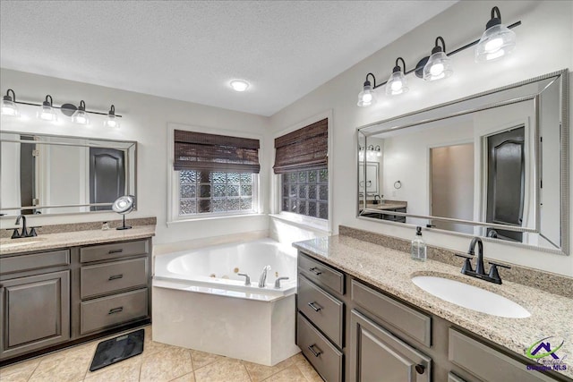 bathroom featuring tile patterned flooring, vanity, a textured ceiling, and a washtub