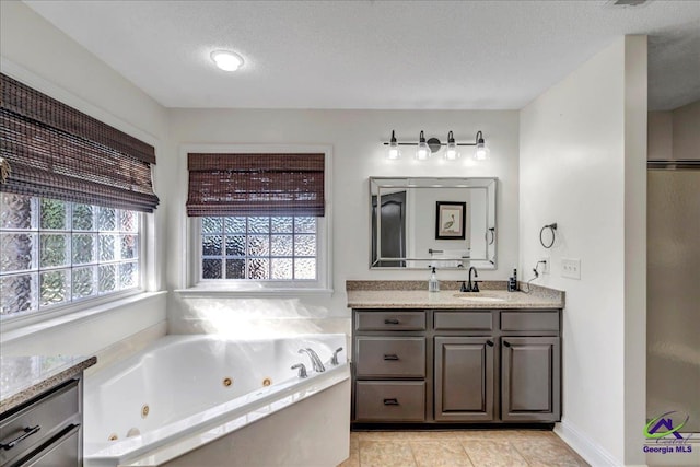 bathroom featuring vanity, a bath, a textured ceiling, and tile patterned floors