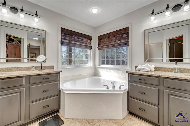 bathroom with tile patterned flooring, vanity, a textured ceiling, and a tub