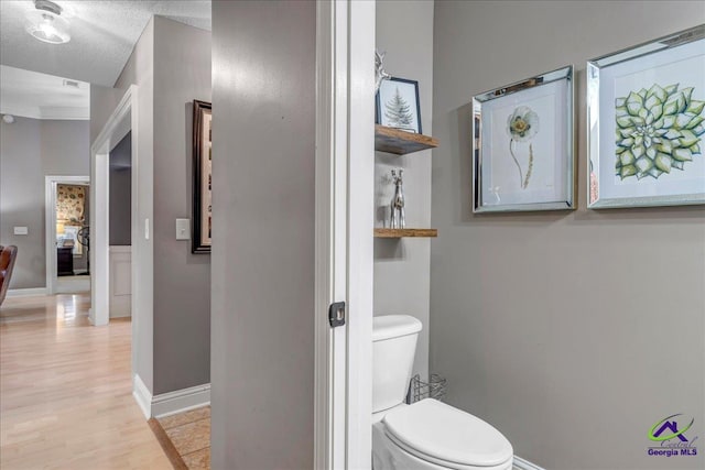 bathroom featuring hardwood / wood-style flooring, toilet, and a textured ceiling