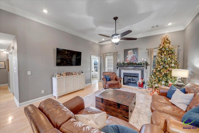 living room with light hardwood / wood-style floors, ceiling fan, and crown molding