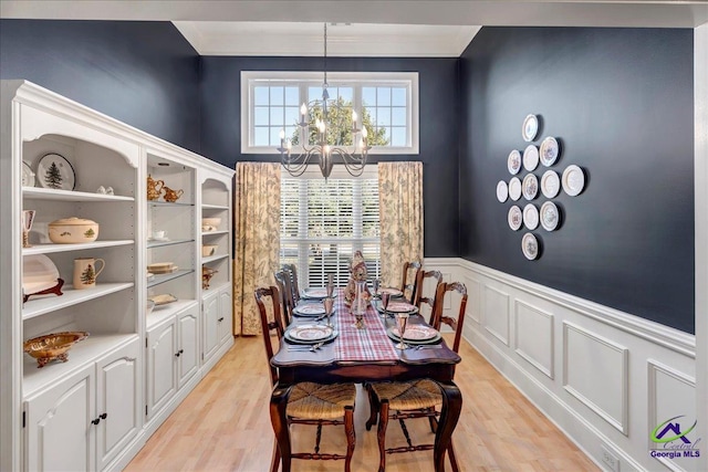 dining room featuring ornamental molding, light wood-type flooring, and an inviting chandelier