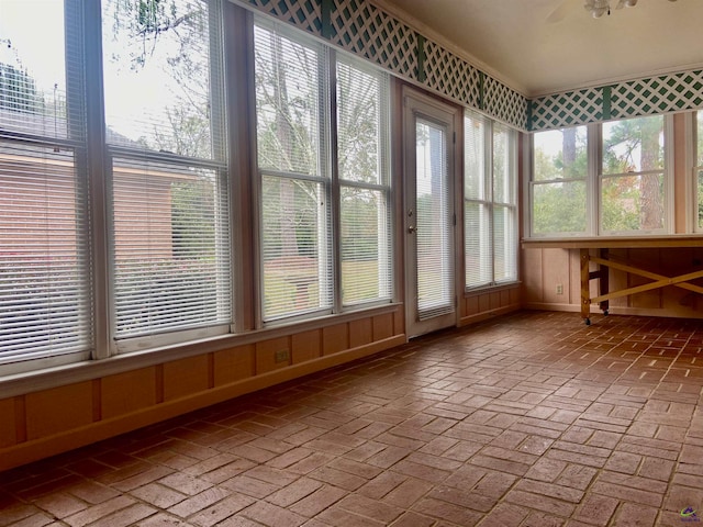 unfurnished sunroom featuring ceiling fan