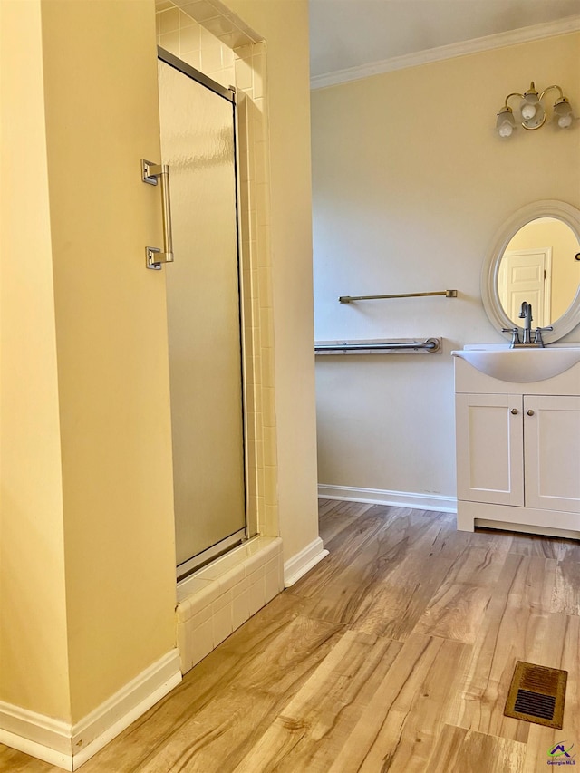 bathroom featuring hardwood / wood-style floors, vanity, a shower with door, and ornamental molding