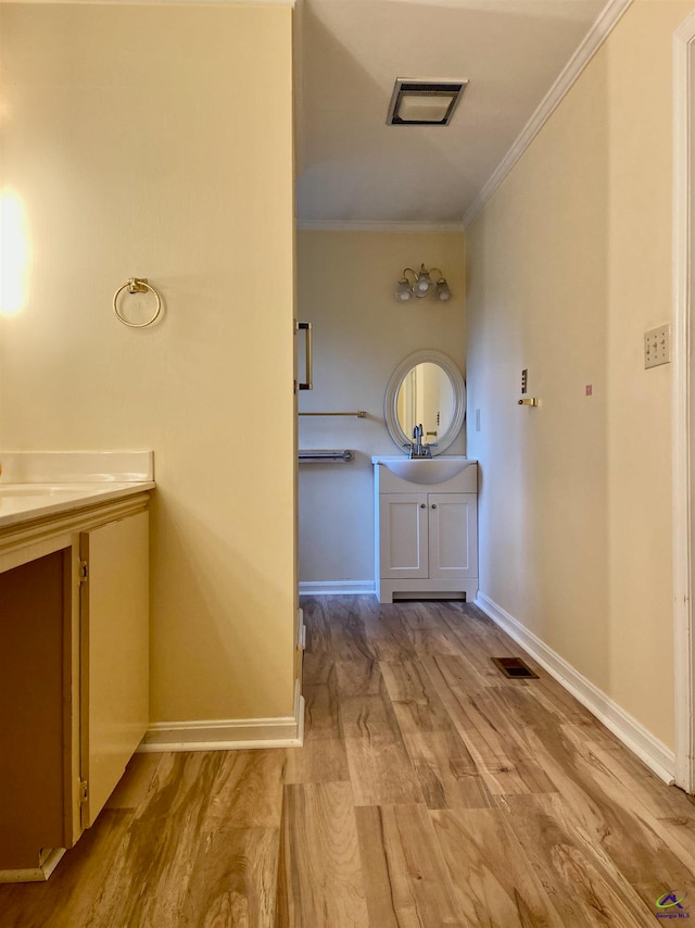 hall with light hardwood / wood-style flooring, crown molding, and sink