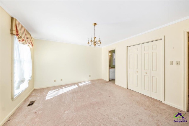 unfurnished bedroom featuring light carpet, a chandelier, a closet, and crown molding