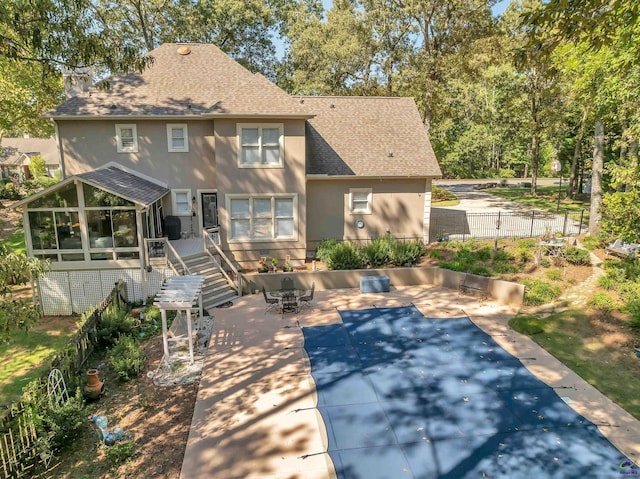 rear view of property with a patio, a covered pool, and a sunroom