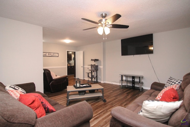 living room featuring ceiling fan, wood-type flooring, and a textured ceiling