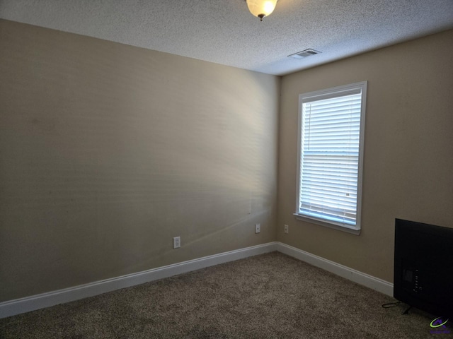 carpeted empty room with a textured ceiling