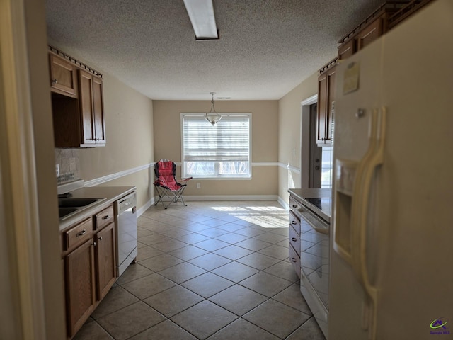 kitchen featuring pendant lighting, white appliances, a textured ceiling, sink, and light tile patterned floors