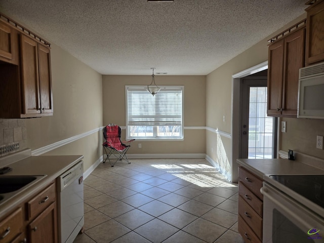 kitchen featuring a textured ceiling, light tile patterned floors, pendant lighting, and white appliances