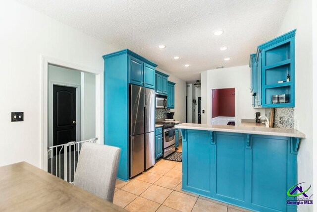 kitchen featuring decorative backsplash, a kitchen bar, blue cabinets, and stainless steel appliances