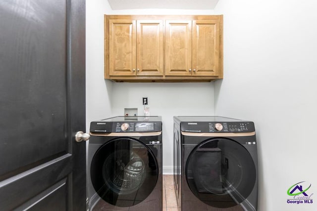 laundry area with washing machine and clothes dryer, tile patterned flooring, and cabinets