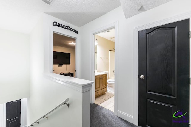 hallway with a textured ceiling and light colored carpet