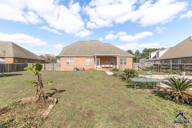 back of property with central air condition unit, a patio area, and a yard