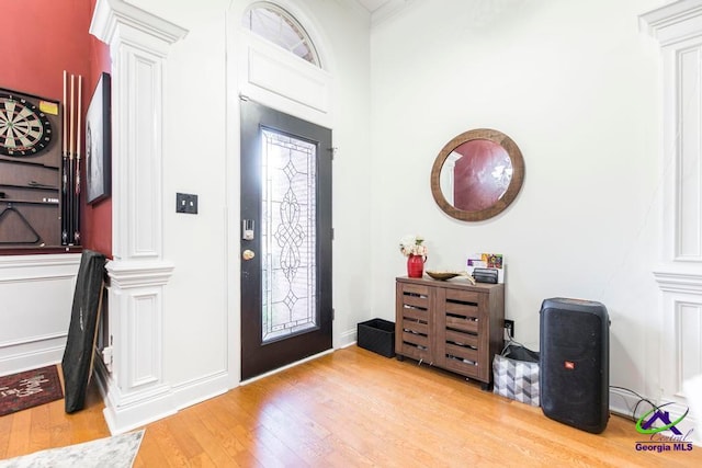 entryway featuring ornate columns, ornamental molding, and light hardwood / wood-style flooring